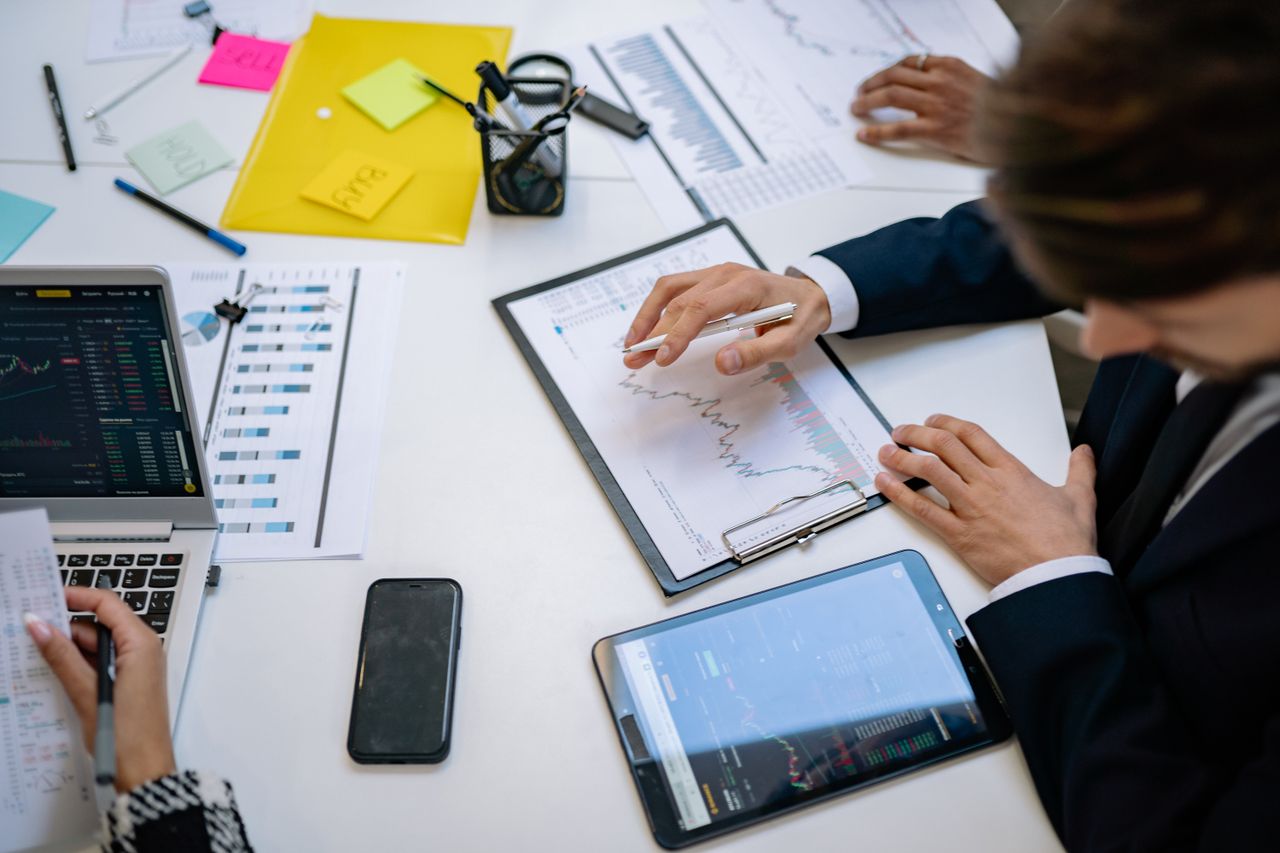 A team is examining financial charts and digital information on tablets in an office environment.